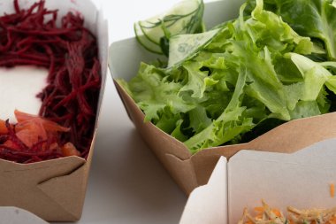 Karton tabaklarda yemeye hazır vejetaryenler ve çiğ gurmeler için farklı salatalar.
