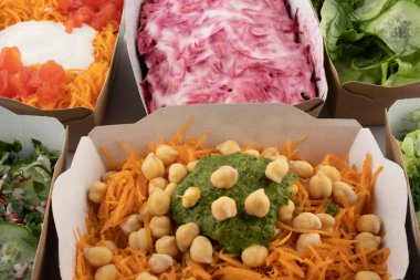 Karton tabaklarda yemeye hazır vejetaryenler ve çiğ gurmeler için farklı salatalar.