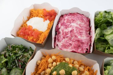 Karton tabaklarda yemeye hazır vejetaryenler ve çiğ gurmeler için farklı salatalar.