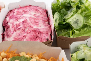 Karton tabaklarda yemeye hazır vejetaryenler ve çiğ gurmeler için farklı salatalar.