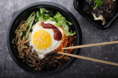 Kore yemeği bibimbap 'ı. Üst görünüm kapalı. Kore çubukları yakınlarda..