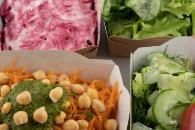 Karton tabaklarda yemeye hazır vejetaryenler ve çiğ gurmeler için farklı salatalar.