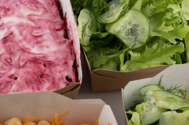 Karton tabaklarda yemeye hazır vejetaryenler ve çiğ gurmeler için farklı salatalar.