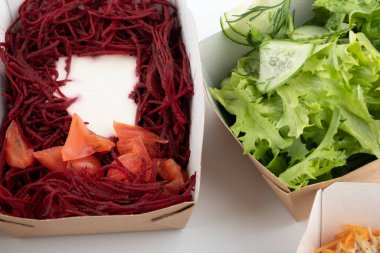 Karton tabaklarda yemeye hazır vejetaryenler ve çiğ gurmeler için farklı salatalar.