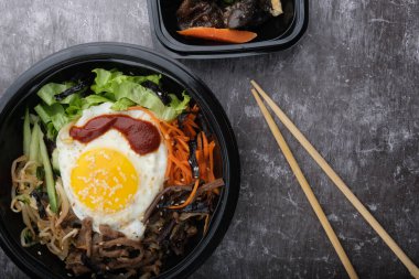 Kore yemeği bibimbap 'ı. Üst görünüm kapalı. Kore çubukları yakınlarda..