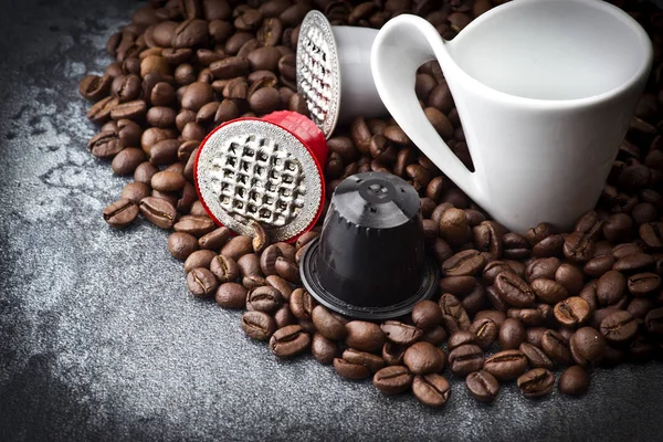 Cápsulas de café expresso sobre os grãos de café — Fotografia de Stock