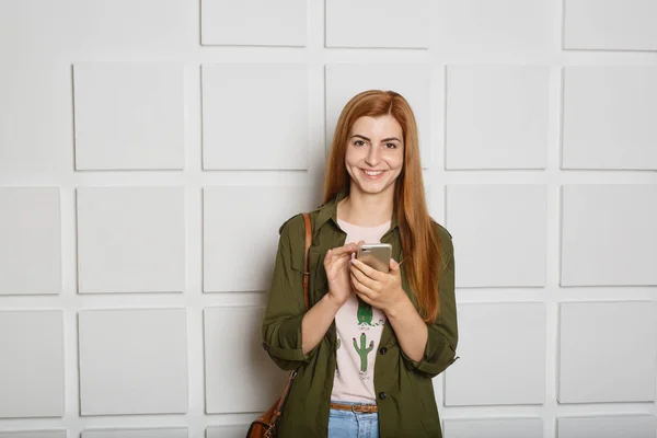 Молодая красивая девушка держит в руках мобильный телефон — стоковое фото