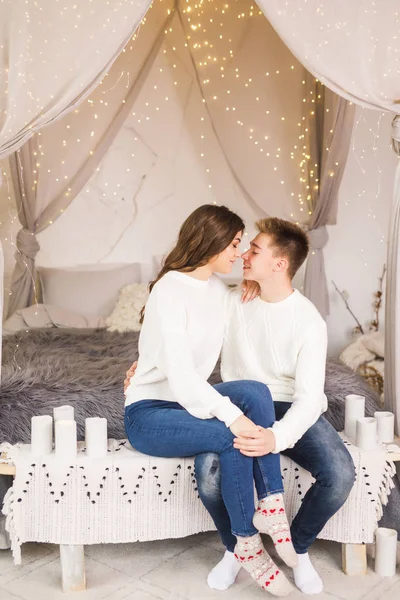 年轻漂亮的夫妇坐在一张漂亮的白色房间的床上 面带微笑 — 图库照片