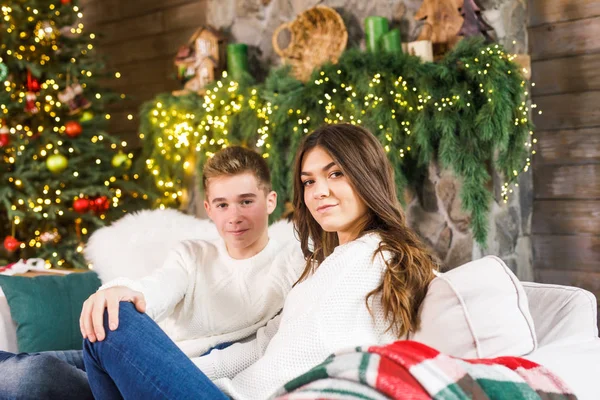 クリスマスツリーを背景にベッドの上の美しい部屋に座って笑っている若い美しいカップル — ストック写真