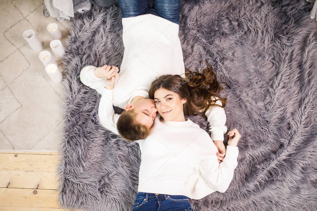 Young beautiful couple lies on the floor in a beautiful white room and smiling