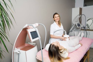 Genç, güzel doktor beyaz takım elbiseli hastaya lpg masajı yapıyor.