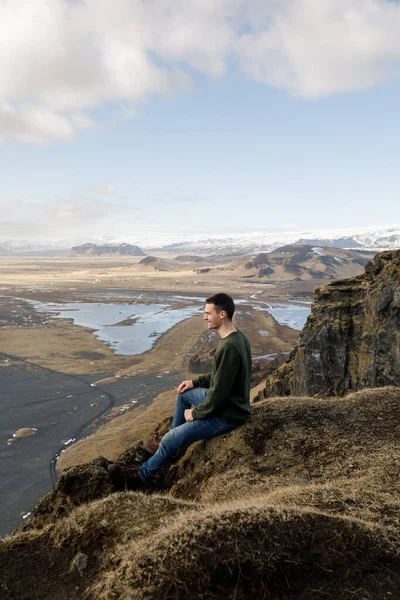 Attractive Young Male Sitting Cliff Black Sand Beach Mountains View — Stock Photo, Image