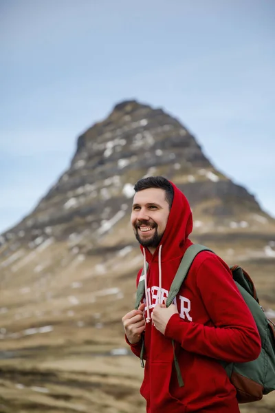 handsome young man walking on grass field in front of Iceland mountains