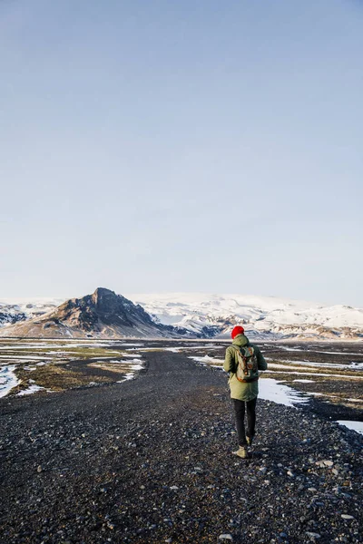joyful man waking on black land on Iceland on mountains background