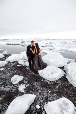 young couple in love walking on snowy black sand beach in Iceland 