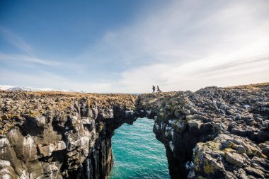 Norveç Denizi 'nin doğal taştan kapısında yürüyen romantik çiftin güzel manzarası