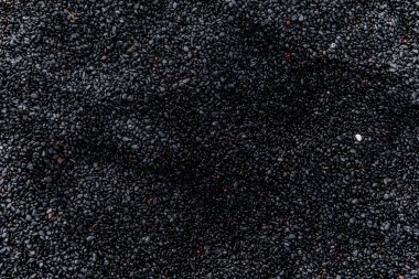 Siyah kumlu İzlanda sahilinin siyah pürüzsüz taşlarıyla yakın görüntüsü. 