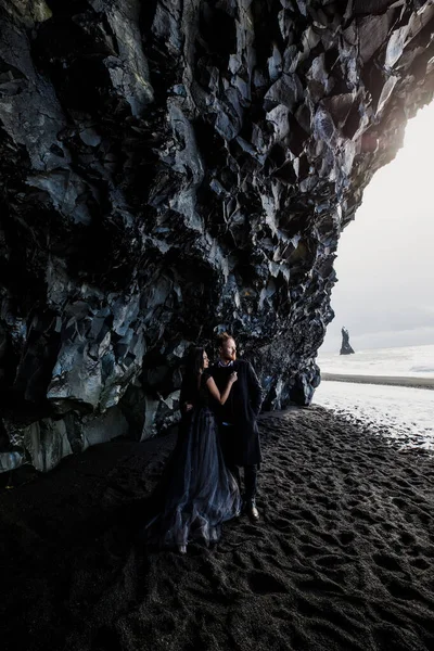 ノルウェーの海にある黒い砂のアイスランドのビーチの近くを歩く恋人たち — ストック写真