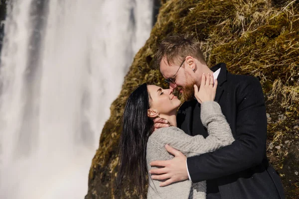 アイスランドの山の滝の近くに抱きつく愛の幸せなカップル — ストック写真
