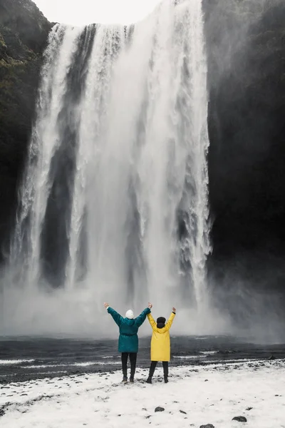 happy and funny couple enjoying big waterfall with in Iceland mountains background