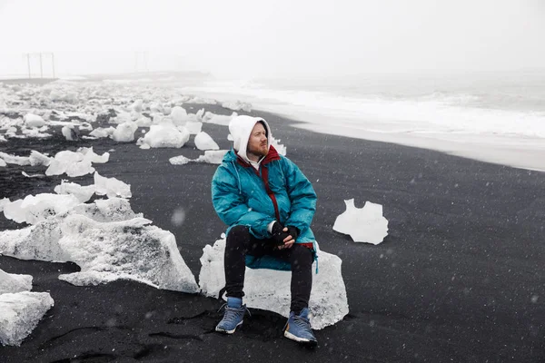 Atractivo Joven Sentado Hielo Sobre Fondo Playa Arena Negra — Foto de Stock