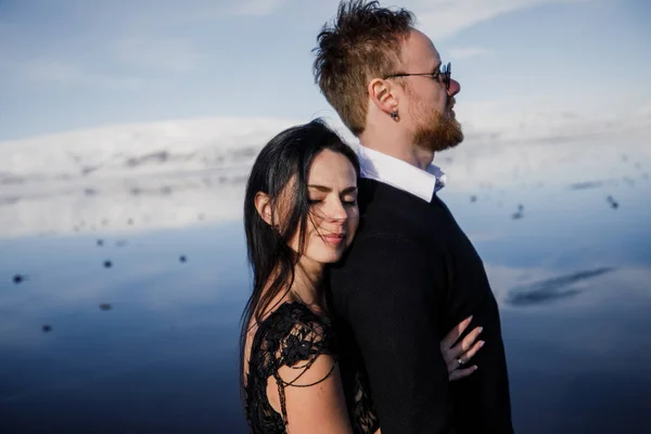 アイスランドの凍った黒砂のビーチでポーズをとる豪華な若いカップル — ストック写真