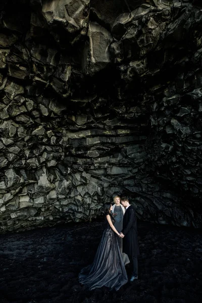 beautiful young woman and man tying the knot in an open air wedding ceremony in Iceland black cave