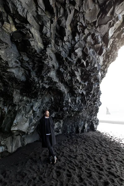 Pohledný Mladý Muž Pózuje Blízkosti Velké Černé Jeskyně Černém Písku — Stock fotografie