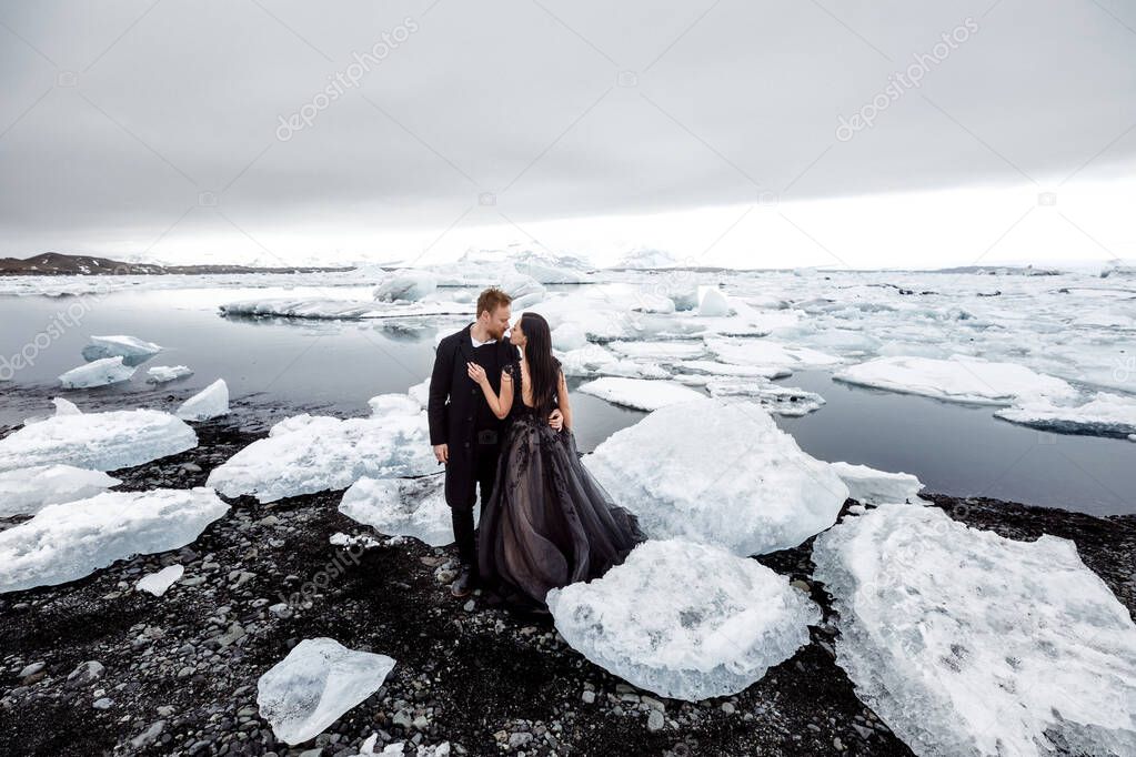 beautiful and happy couple posing on snowy and frozen black sand beach in Iceland 