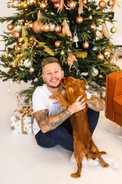 Beyaz elbiseli genç bir çift dairelerinde küçük bir köpekle eğleniyorlar.