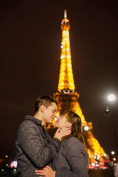 若い美しいカップルは スタイリッシュな服装 灰色のコートの少女 灰色のコートの男はエッフェル塔の近くの夜にパリを歩いています — ストック写真