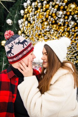 Noel süslenmiş ağaç ve buz pateni sahasında poz veren genç çiftlerin portreleri