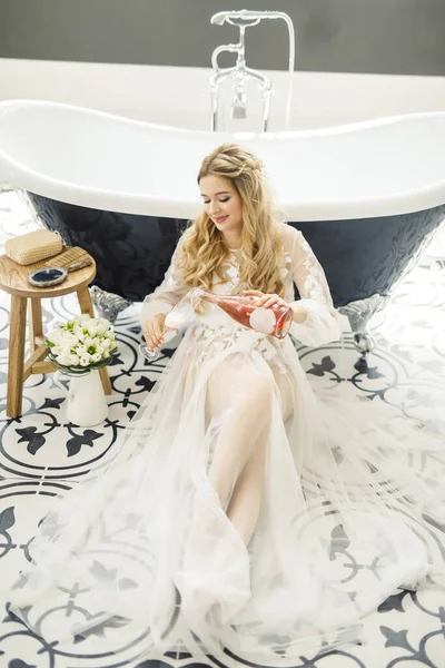 一个年轻美丽的金发新娘的肖像 浴室里有一瓶香槟 — 图库照片