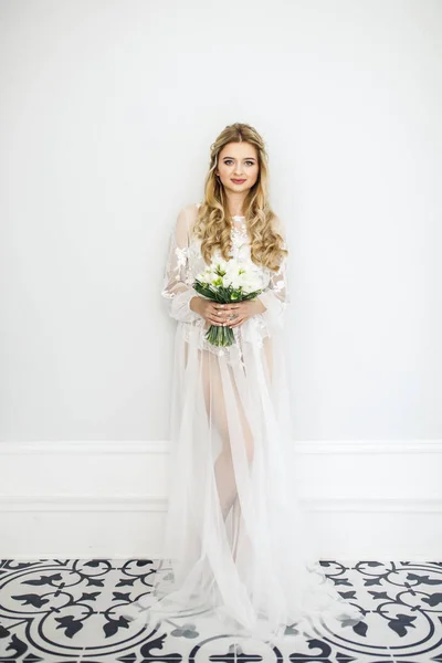 一个年轻美丽的金发新娘的画像 她在一个白色的房间里带着一束鲜花 — 图库照片