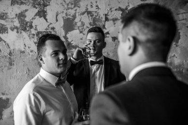 Beyaz gömlekli üç adam çatı katında viski içiyor.