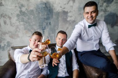 Beyaz gömlekli üç adam çatı katında viski içiyor.