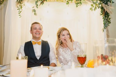 Düğün çifti gelin ve damat bir restoranda bir masaya otururlar.