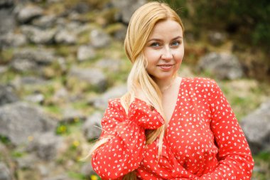 Polonya 'daki Tatra Ulusal Parkı' nda kırmızı elbiseli genç bir kız bir taşın üzerinde oturuyor.