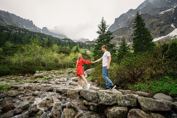 若いカップル赤いドレスの女の子白いTシャツと青いパンツの男がポルシャのタトラ国立公園を歩いています — ストック写真