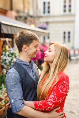 Genç bir çift şık giyiniyor, kırmızı elbiseli bir kız, mavi gömlekli ve mavi pantolonlu bir adam, Krakow Polonya sokaklarında yürüyor.