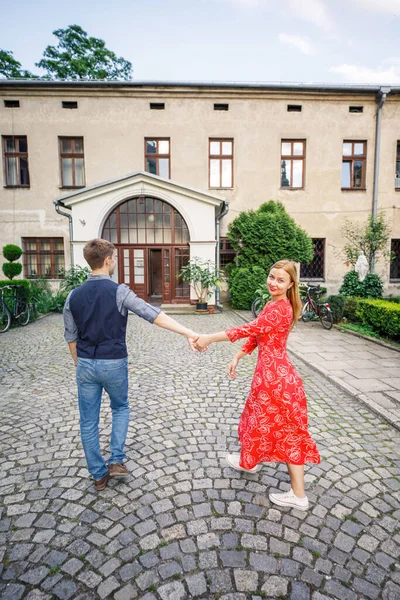 若いカップルはスタイリッシュに服を着て赤いドレスの女の子青いシャツと青いパンツの男イタリアの通りを歩く — ストック写真