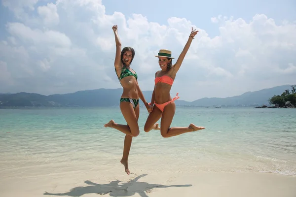 Duas meninas hipster na moda legal pulando na praia desfrutando de férias em uma ilha tropical, corpo bronzeado perfeito, desgaste casual sexy elegante, biquínis — Fotografia de Stock