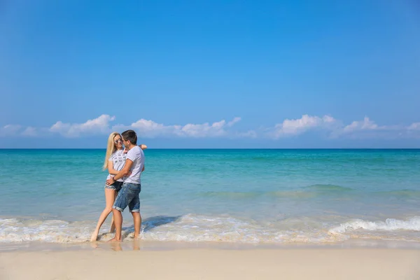 Jovem casal feliz na praia sorrindo segurando um ao lado do outro. História de amor — Fotografia de Stock