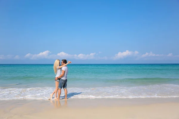 Jovem casal feliz na praia sorrindo segurando um ao lado do outro. História de amor — Fotografia de Stock