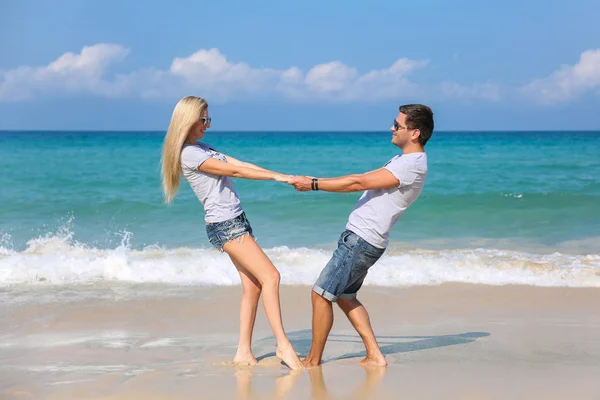 Jovem casal feliz na praia sorrindo de mãos dadas um ao outro. História de amor — Fotografia de Stock