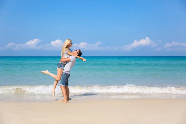 Jovem casal feliz na praia sorrindo segurando um ao lado do outro. História de amor — Fotografia de Stock