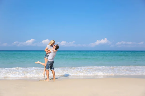 Jovem casal feliz na praia sorrindo segurando um ao lado do outro. História de amor — Fotografia de Stock