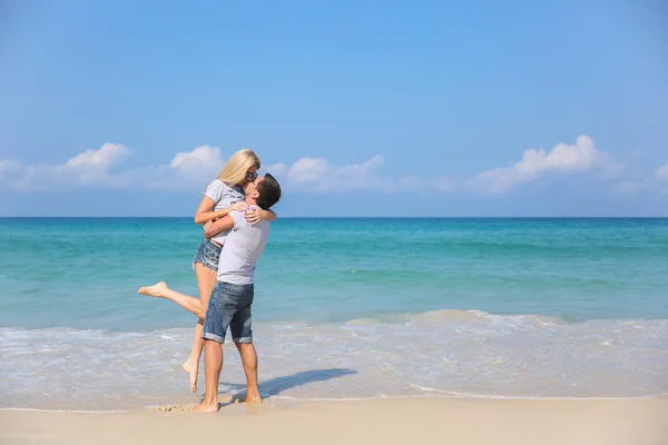 Giovane coppia felice sulla spiaggia sorridente stretta intorno a vicenda. Storia d'amore — Foto Stock