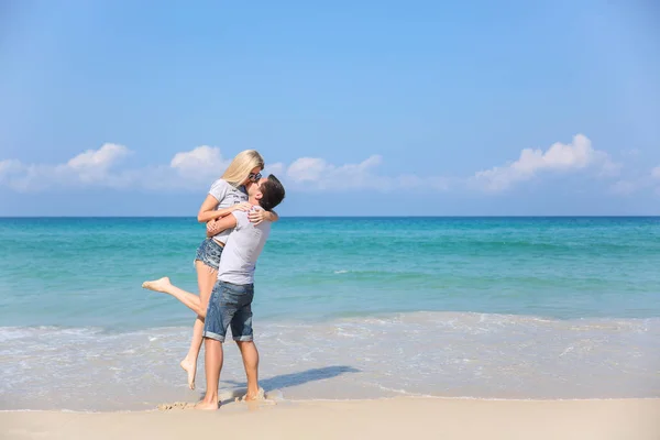 Jovem casal feliz na praia sorrindo segurando um ao lado do outro. História de amor — Fotografia de Stock