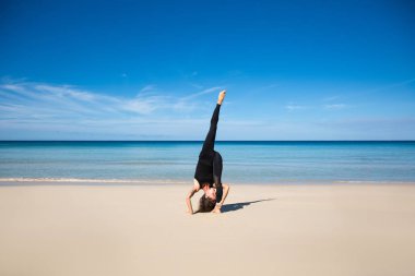 Plaj, ince sportif gövde eğitim, eğlence ve meditasyon, tatil, spor, sağlık kavram, doğal arka plan mavi gökyüzü ve denizin üzerinde sağlıklı yoga egzersiz. Ashtanga kursuna katıldıktan sonra vinyasa